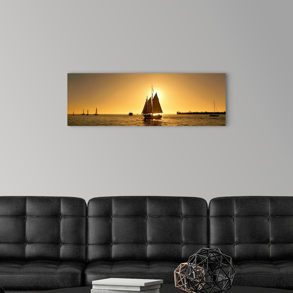 A modern room featuring A sail boat with multiple masts photographed at sunset it in the Florida Keys on panoramic wall art.
