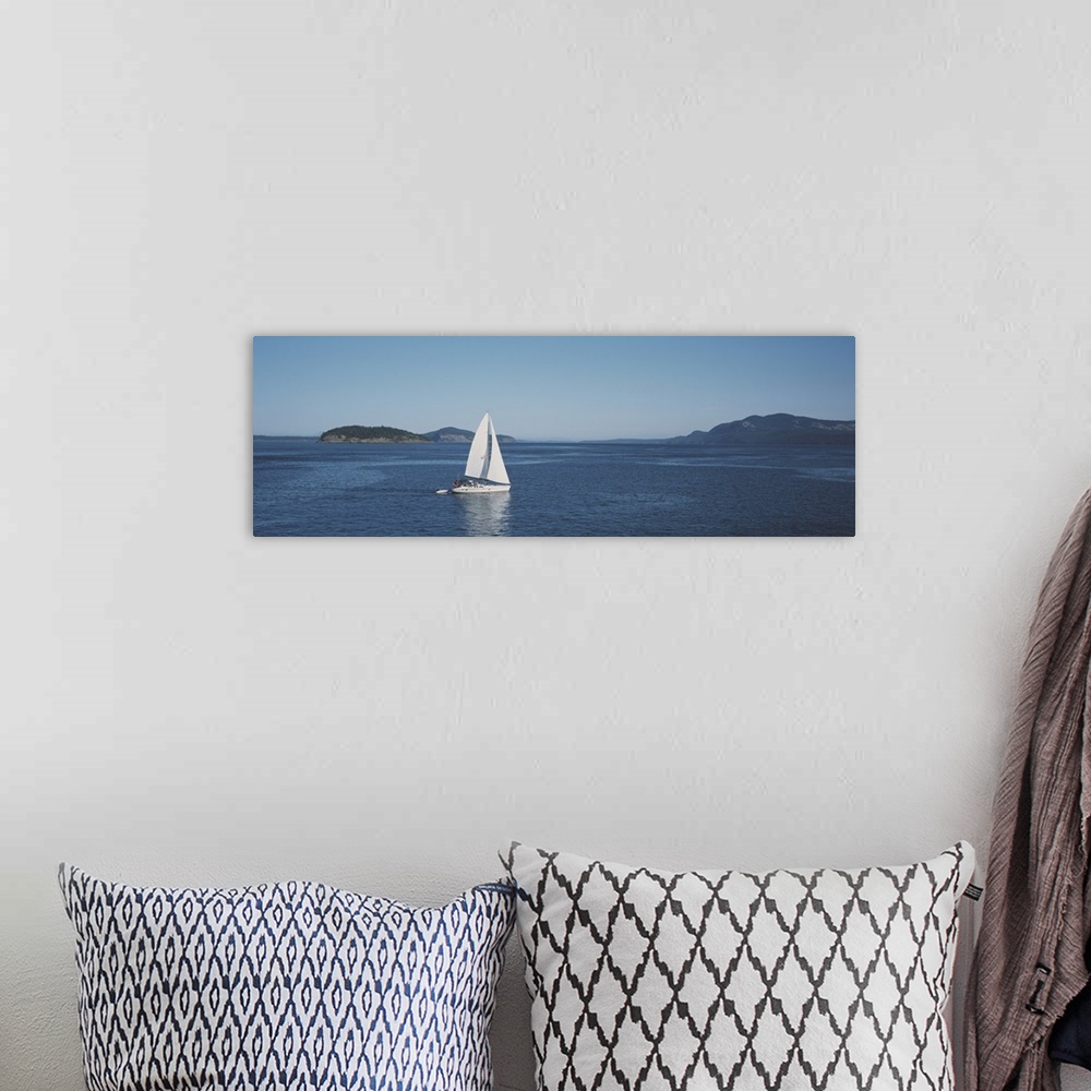A bohemian room featuring Horizontal and narrow photo on canvas of a sailboat sailing in the ocean with islands covered in ...
