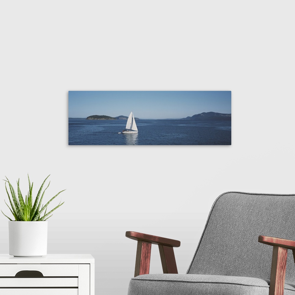 A modern room featuring Horizontal and narrow photo on canvas of a sailboat sailing in the ocean with islands covered in ...