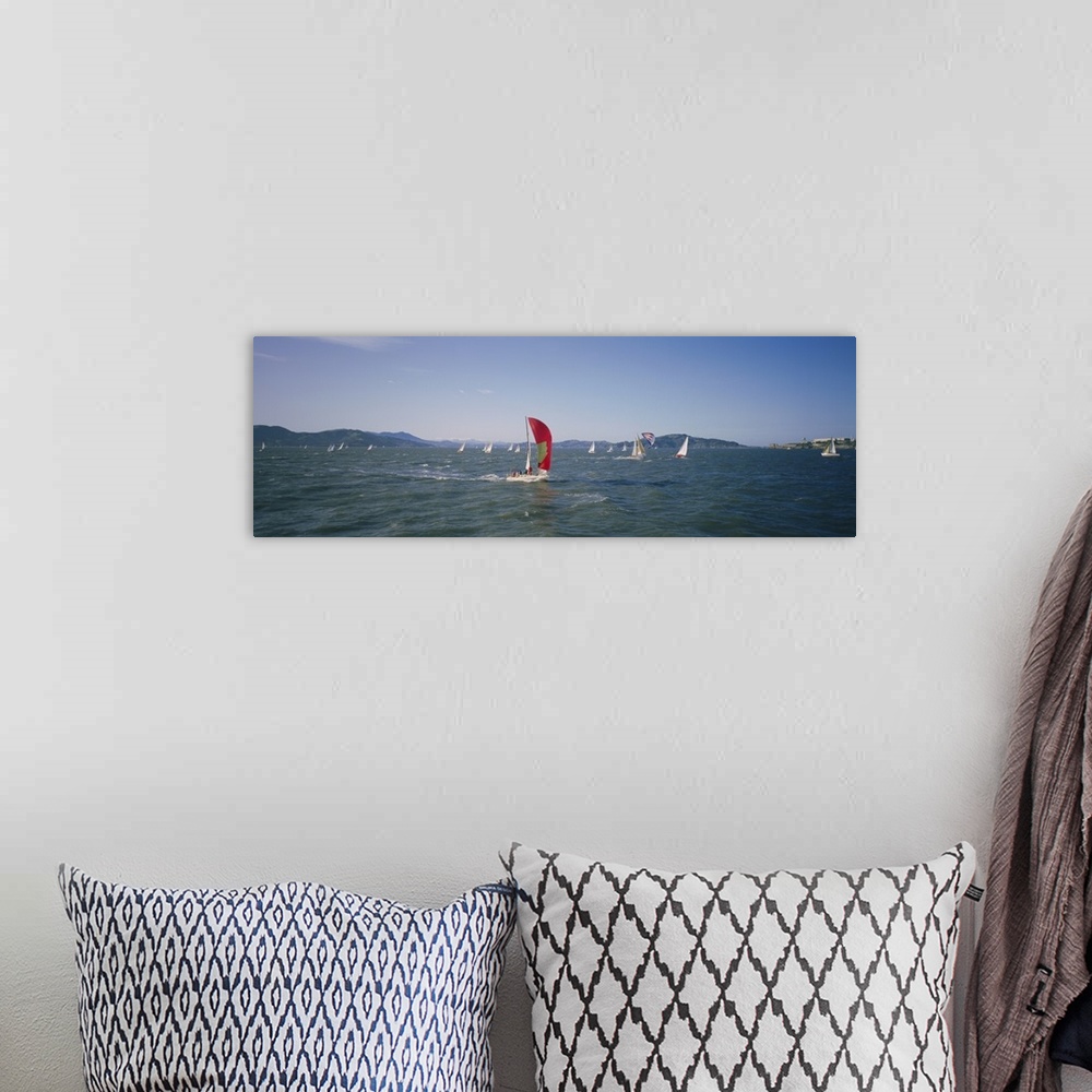 A bohemian room featuring Panoramic photograph ocean with scattered boats with sails and mountains in the distance under a ...