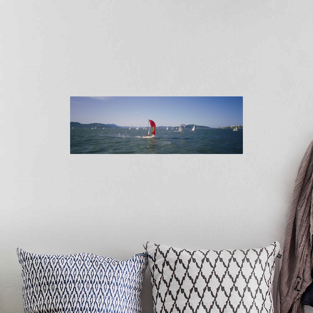 A bohemian room featuring Panoramic photograph ocean with scattered boats with sails and mountains in the distance under a ...