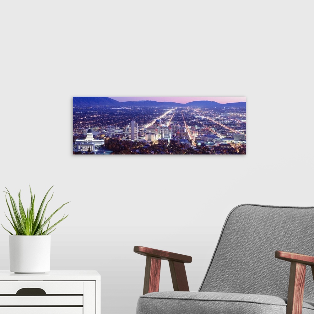 A modern room featuring Panoramic aerial photograph of city lit up at  night with mountain silhouettes in the distance.
