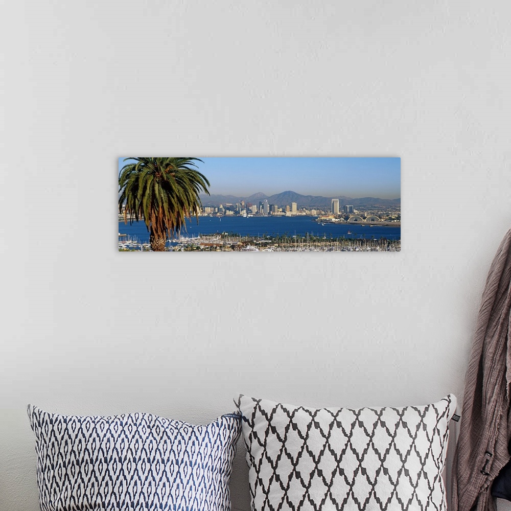 A bohemian room featuring A large panoramic view of the San Diego skyline with water shown in front and sail boats standing...