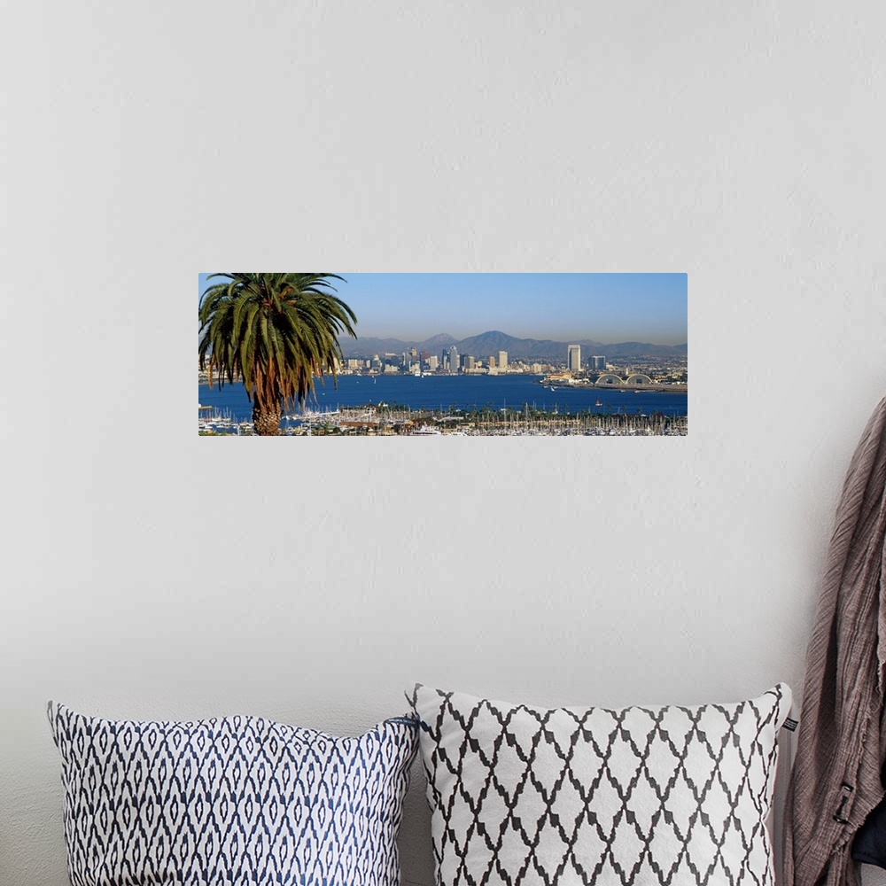 A bohemian room featuring A large panoramic view of the San Diego skyline with water shown in front and sail boats standing...