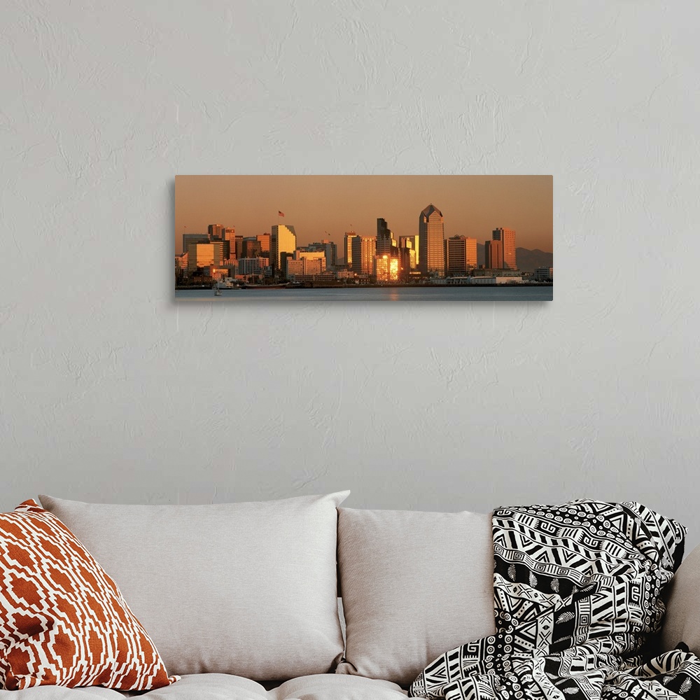 A bohemian room featuring This wall art is a panoramic photograph of the city skyline reflecting the fading sunlight.