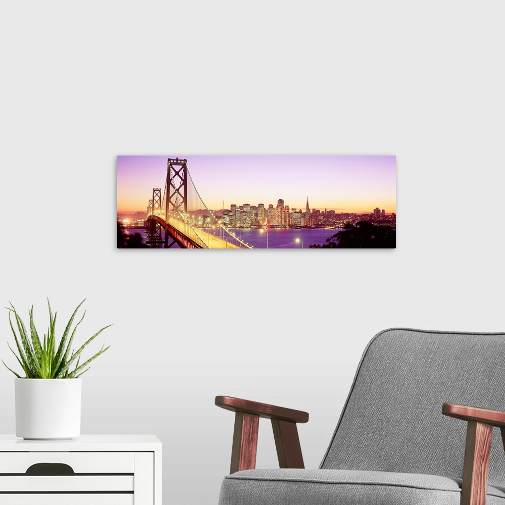 A modern room featuring An aerial photograph on panoramic wall art showing the Golden Gate Bridge and the city skyline in...