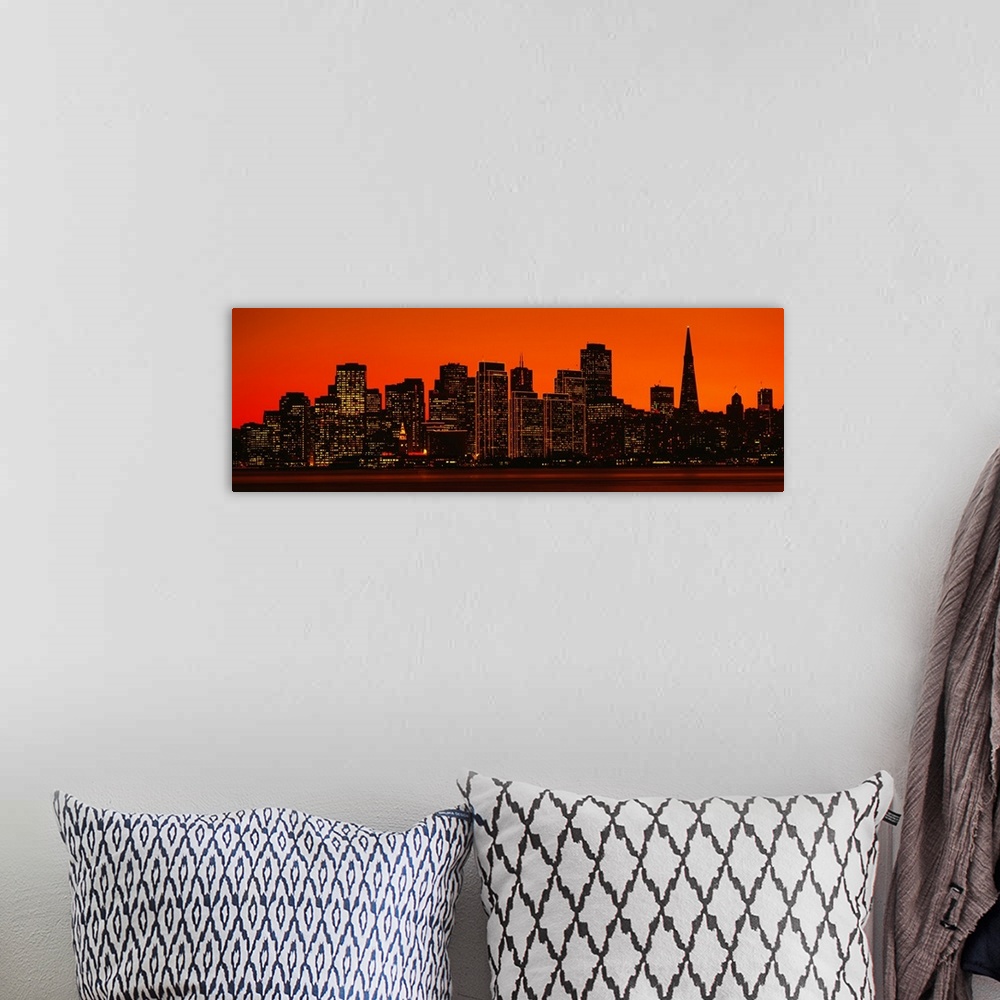 A bohemian room featuring The skyline in San Francisco is pictured in wide angle view with a warm background silhouetting t...