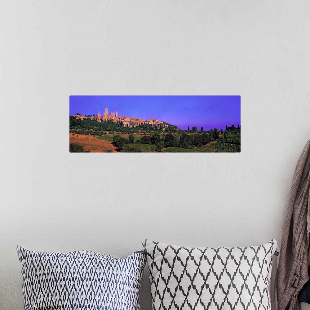A bohemian room featuring Wide angle photograph of San Gimignano in the distance, against a vibrant sky. Green landscape an...