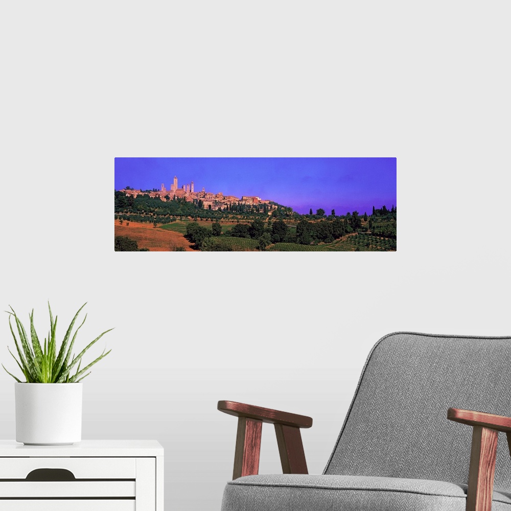 A modern room featuring Wide angle photograph of San Gimignano in the distance, against a vibrant sky. Green landscape an...