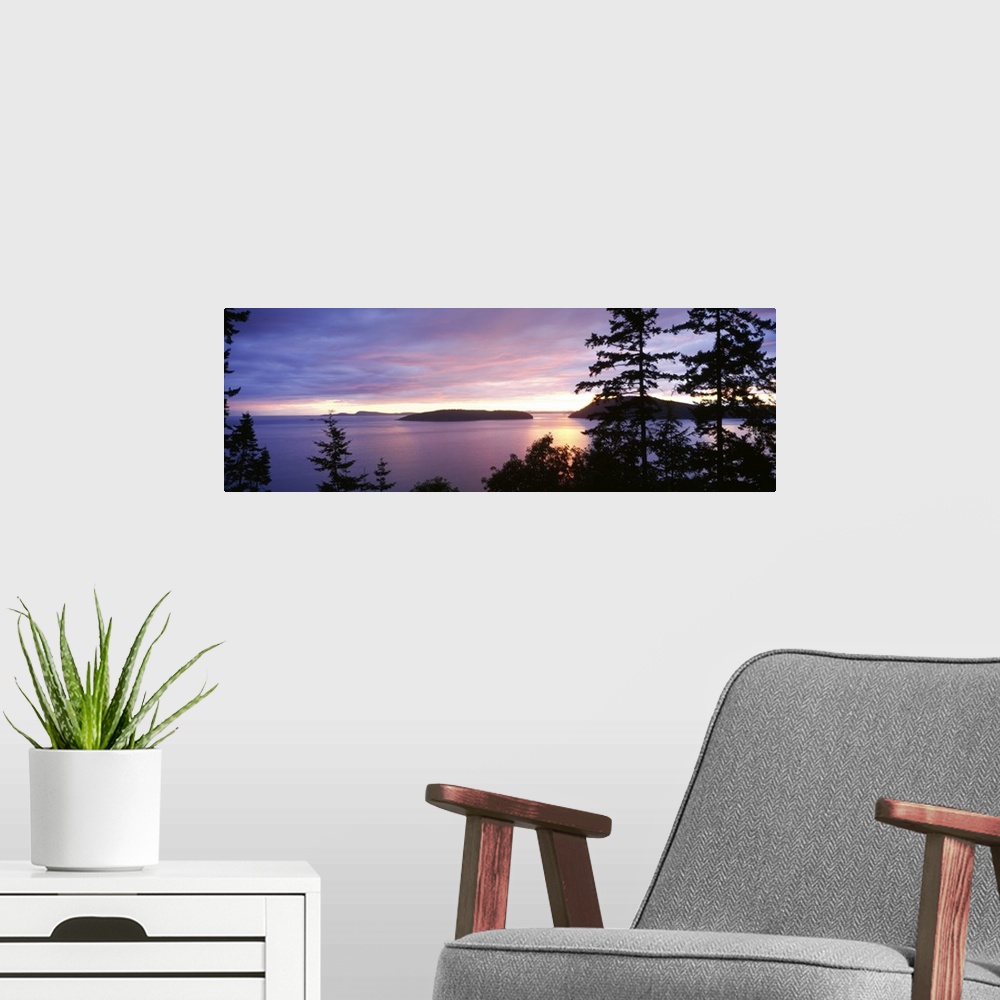 A modern room featuring The sunsets below on the ocean in this landscape photograph of small isles off the coast of Washi...