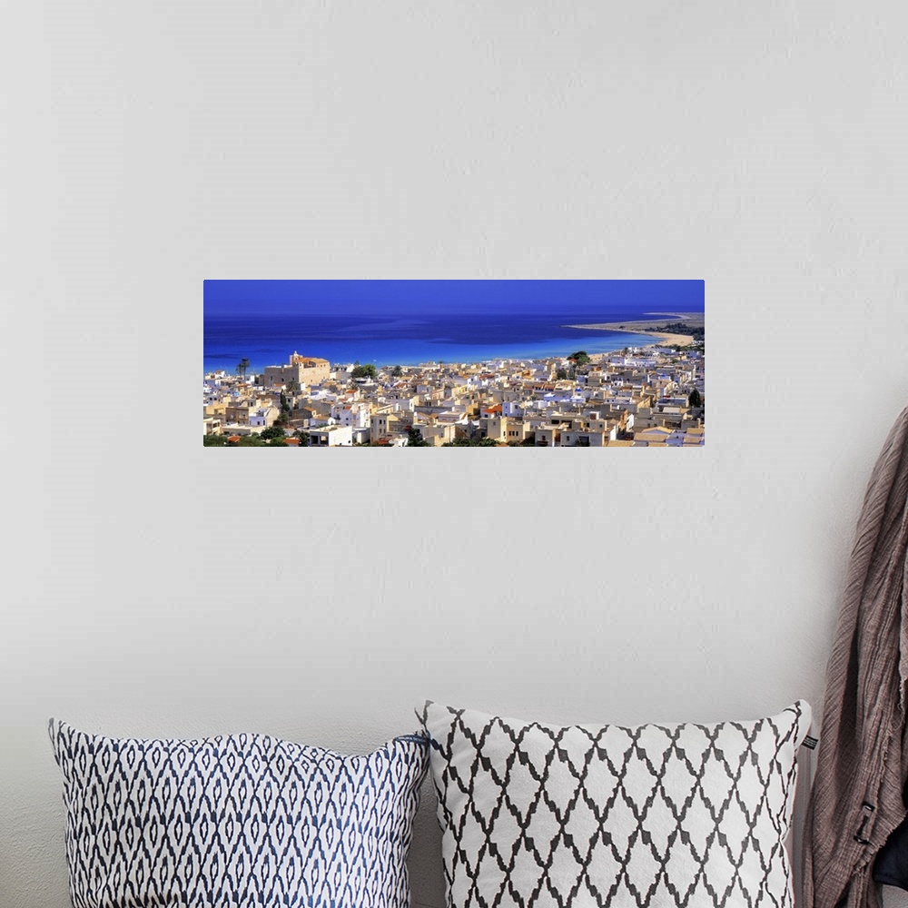 A bohemian room featuring This is a landscape photograph of a coastal village and the sea beyond it in this panoramic wall ...