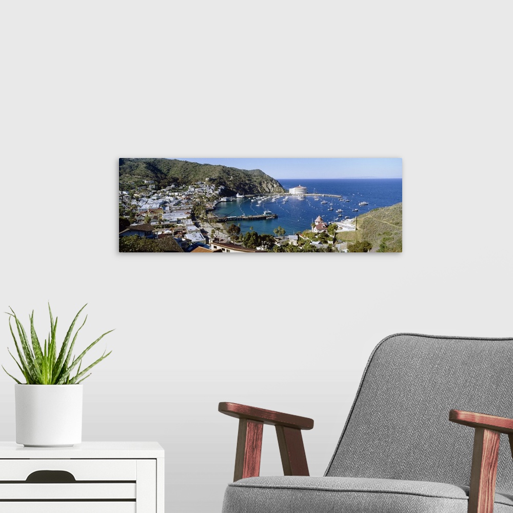 A modern room featuring A Pacific coast harbor photographed from a hill side shows numerous docked boats and various buil...