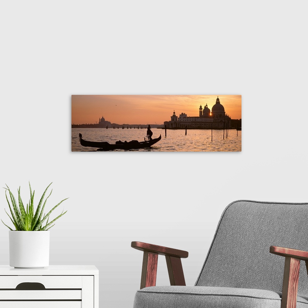 A modern room featuring Panoramic photograph of gondola on waterway with cityscape in background at sunset.