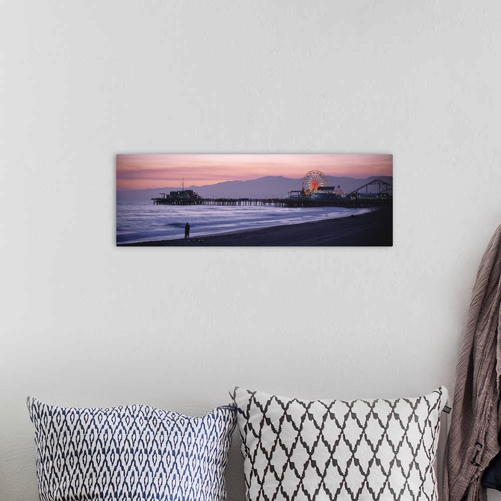A bohemian room featuring A panoramic shot taken of the Santa Monica pier during sun down with a couple standing on the bea...