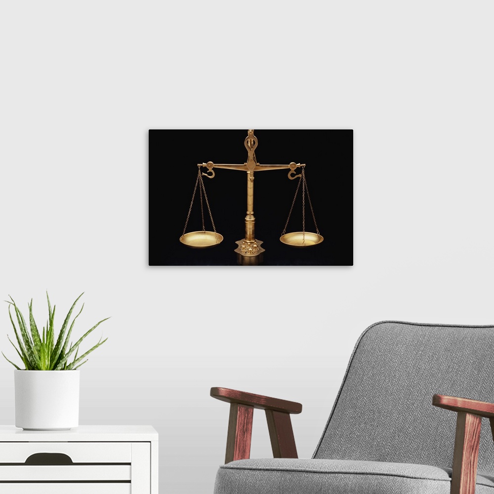 A modern room featuring Photograph taken of gold scales of justice against a black background.