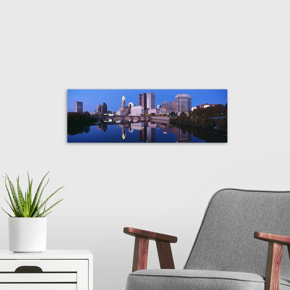 A modern room featuring Scioto River and Columbus Ohio skyline, the capital city, at dusk with lights on