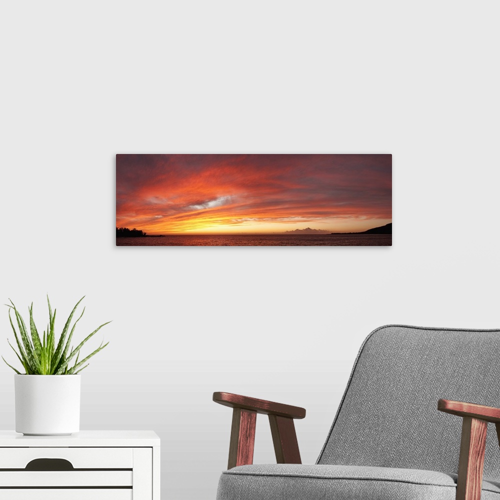 A modern room featuring View of the Pacific ocean at sundown. The setting sun creates a glowing light on the clouds above...