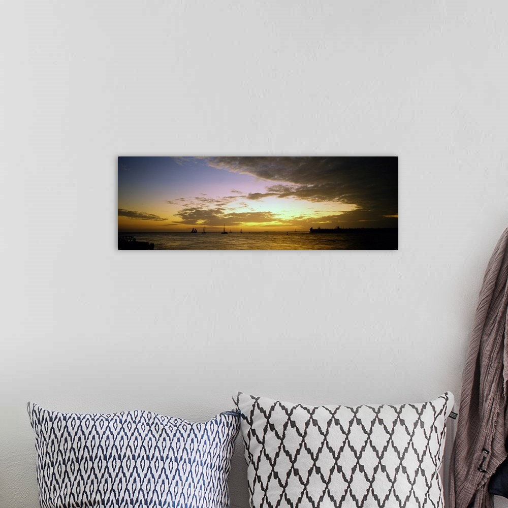 A bohemian room featuring Panoramic photograph of ocean with sailboats in the distance under a cloudy sky at dusk.