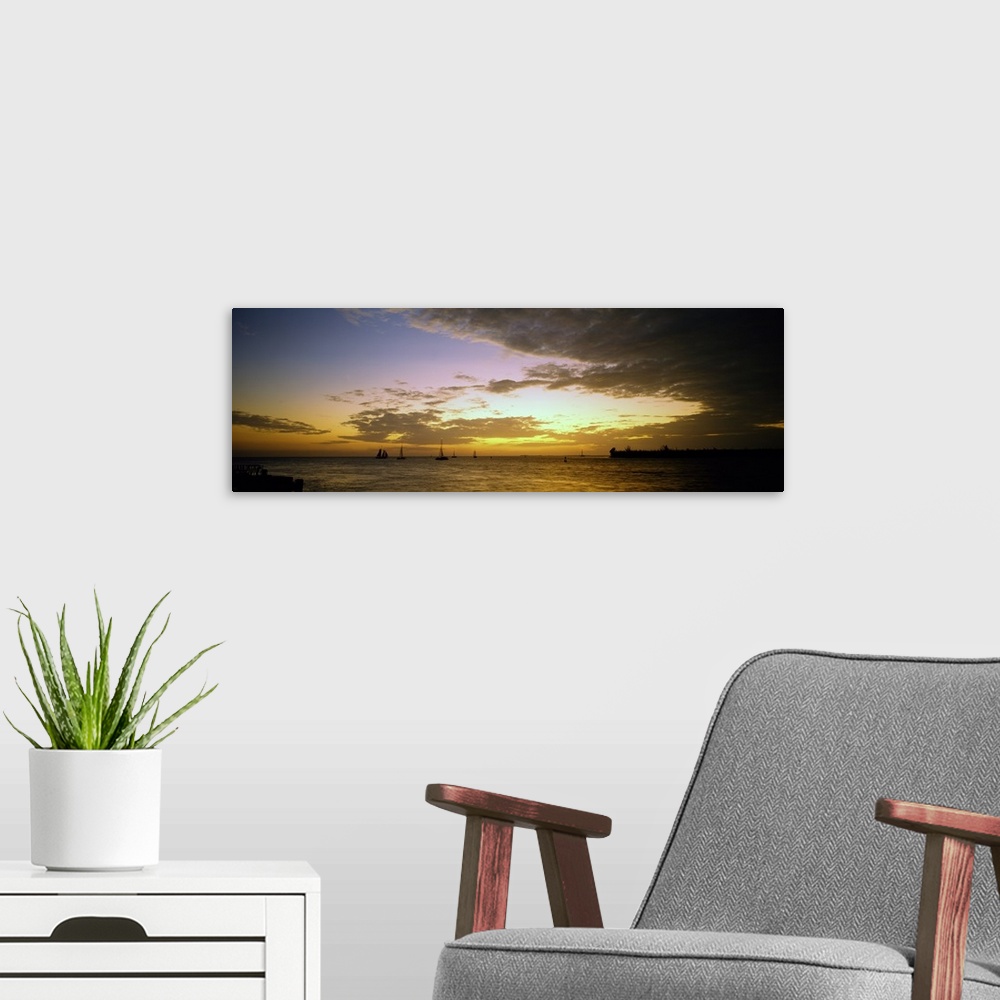 A modern room featuring Panoramic photograph of ocean with sailboats in the distance under a cloudy sky at dusk.