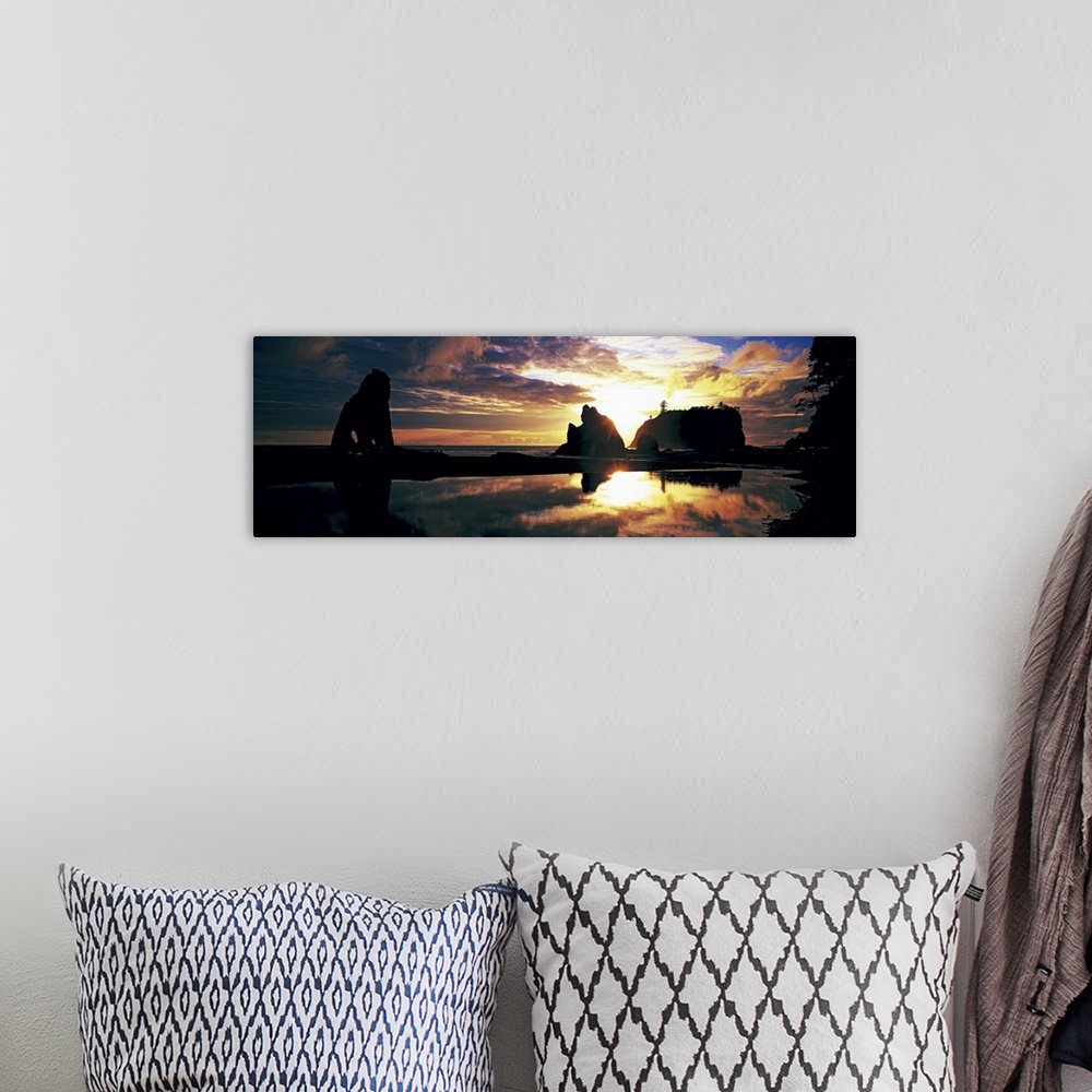 A bohemian room featuring Panoramic photograph of huge rock formations in the ocean under a dark cloudy sky at sunset.
