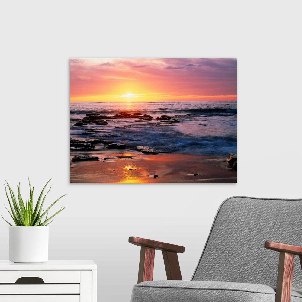 A modern room featuring Photograph of rocky shoreline at sunset with a cloudy sky.