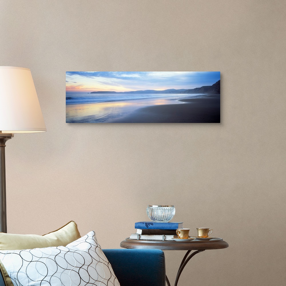 A traditional room featuring Panoramic photograph shows waves slowly crashing into a section of a beach.  In the background is...
