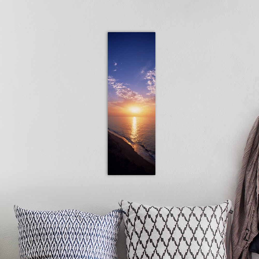 A bohemian room featuring Vertical panorama of the sun rising on the horizon of the Atlantic ocean, as seen from a sandy be...