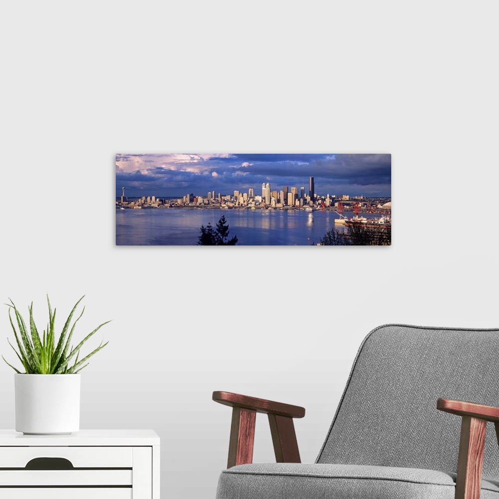 A modern room featuring Panoramic, distant photograph over the water of the Seattle skyline, beneath a sky full of large,...