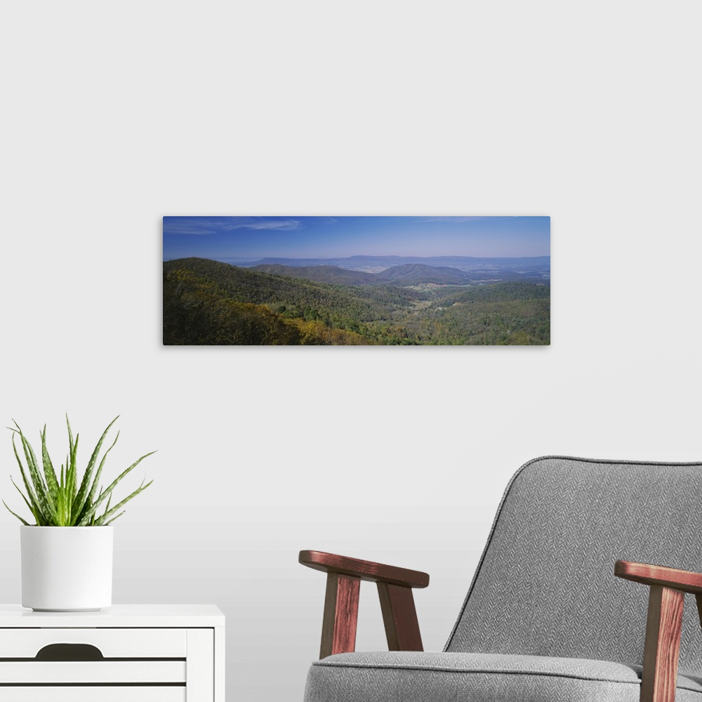 A modern room featuring Panoramic view of the sprawling forest over the hilly landscape of Virginia on a clear, sunny day.
