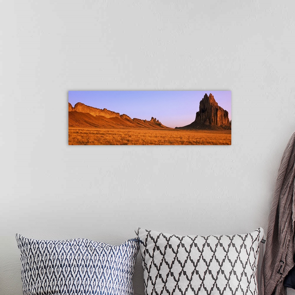 A bohemian room featuring Ship Rock mountain is skewed to the right side of this panoramic piece with vast desert terrain t...