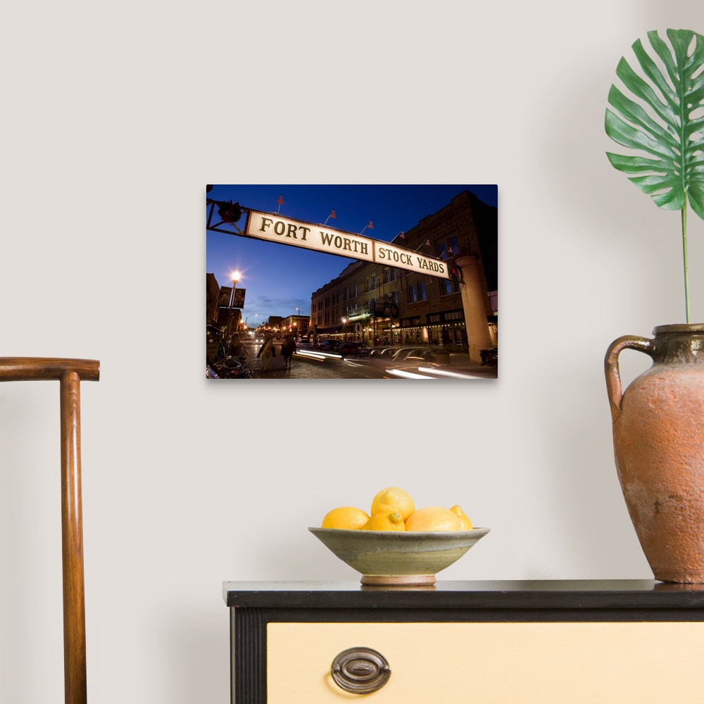 A traditional room featuring Landscape photograph of the Fort Worth Stock Yards sign over a road lined with buildings, at dusk...