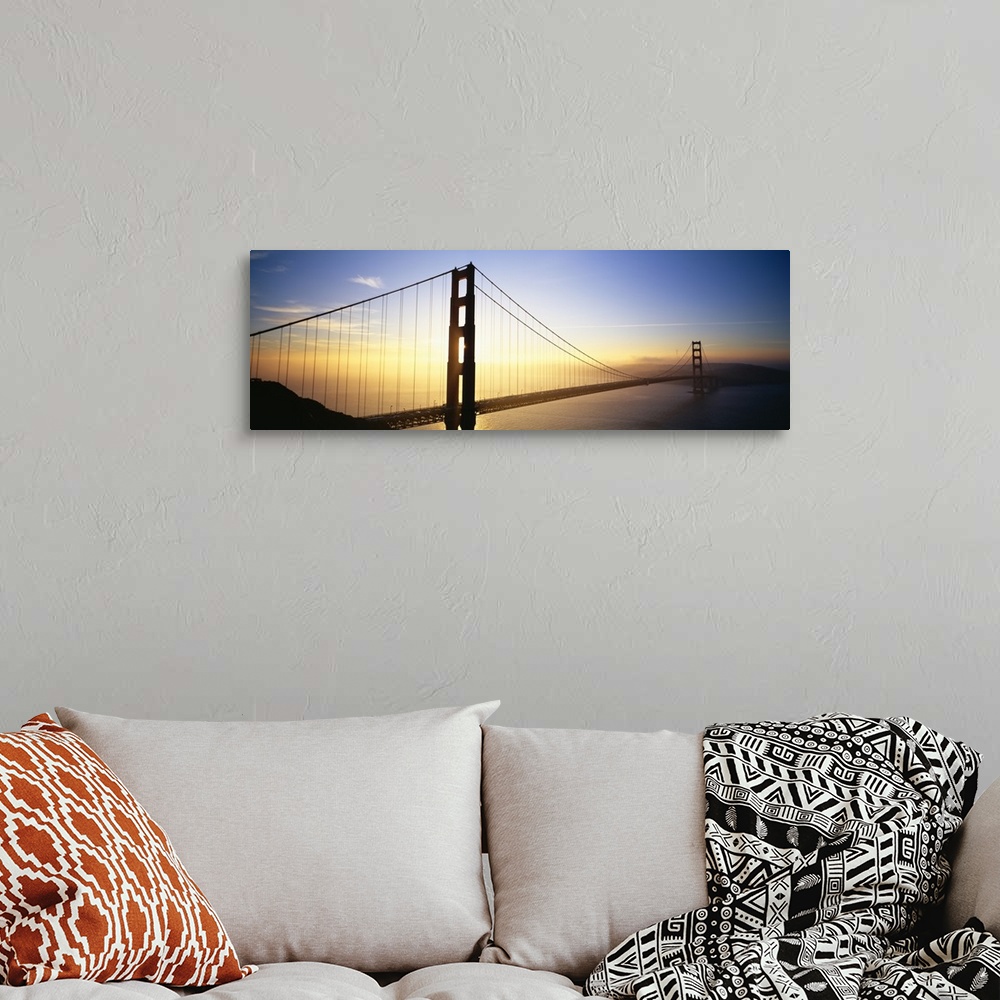 A bohemian room featuring Panoramic, angled photograph of the Golden Gate Bridge, silhouetted as the sun rises in the sky o...