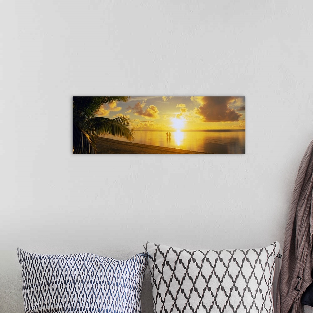 A bohemian room featuring A panoramic photograph of the sun setting over a tropical sea and cloud filled sky with palm tree...