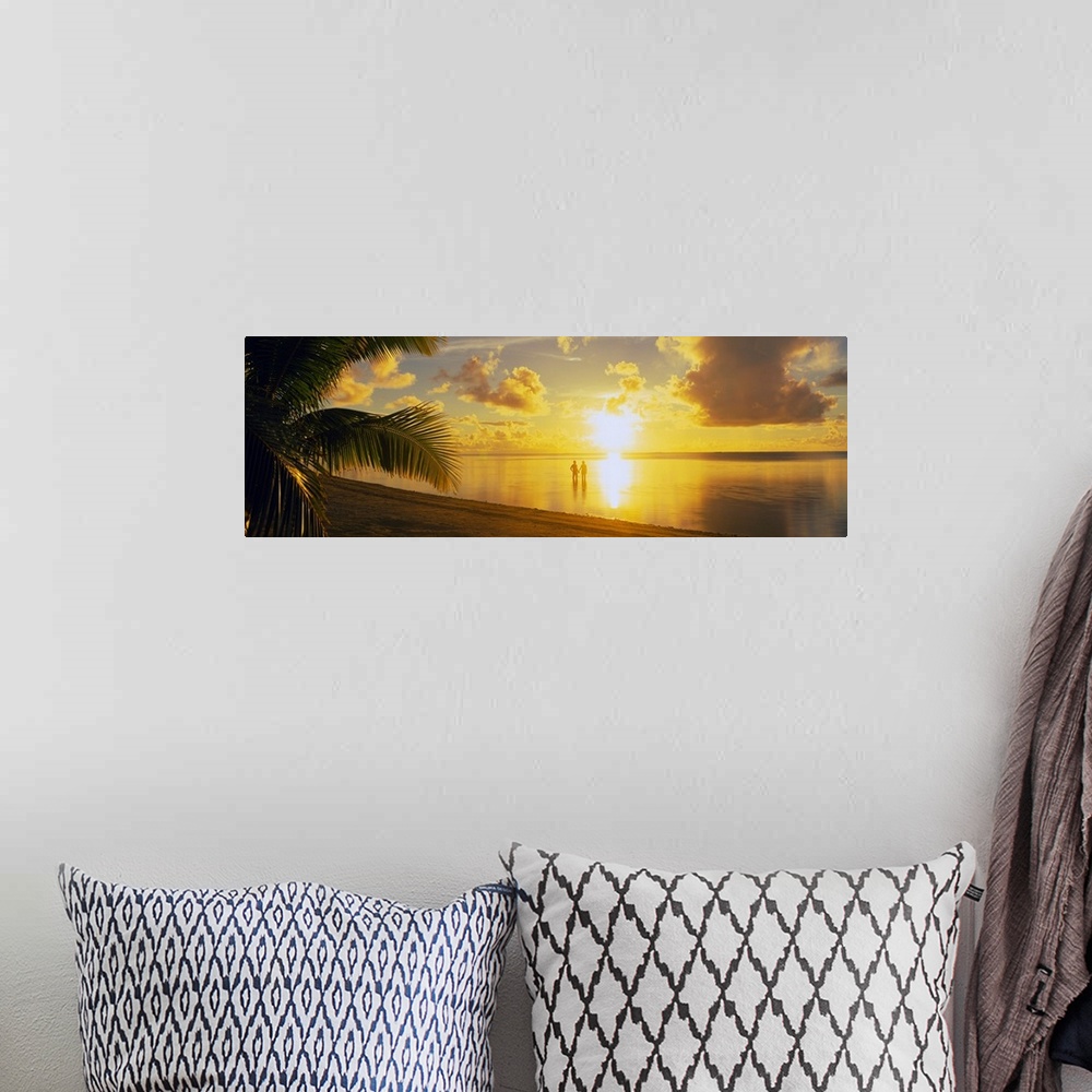 A bohemian room featuring A panoramic photograph of the sun setting over a tropical sea and cloud filled sky with palm tree...