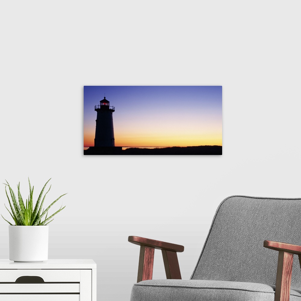 A modern room featuring Wall docor of the silhouette of a lighthouse against a bright sunset.