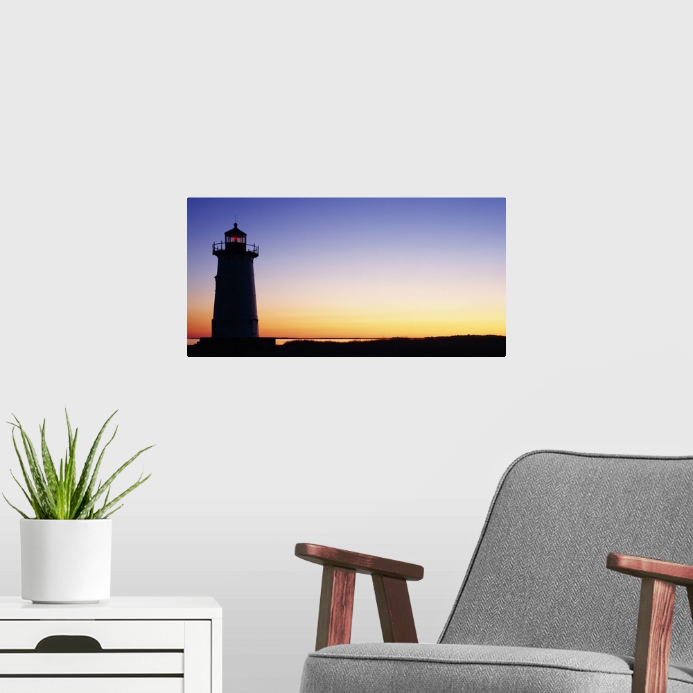 A modern room featuring Wall docor of the silhouette of a lighthouse against a bright sunset.