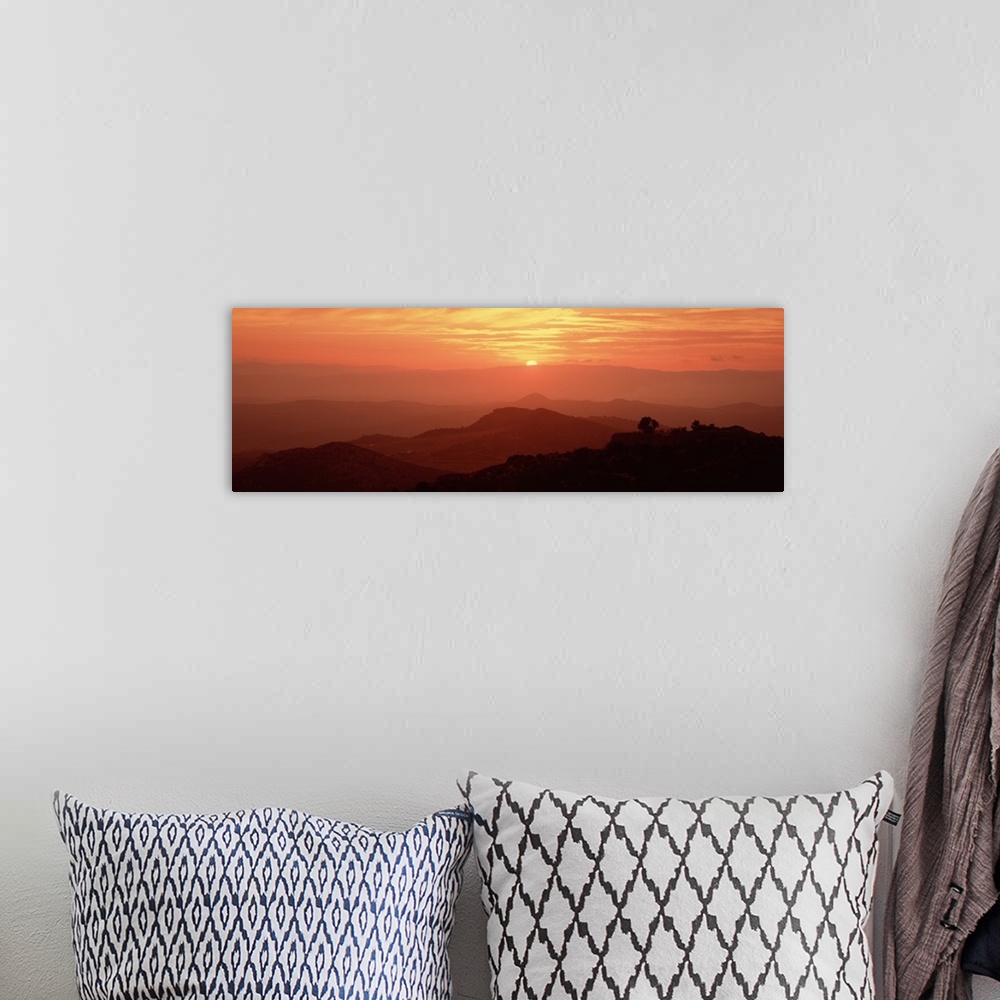 A bohemian room featuring Giant panoramic photo on canvas of layers of Italian hills with a setting sun in the distance.