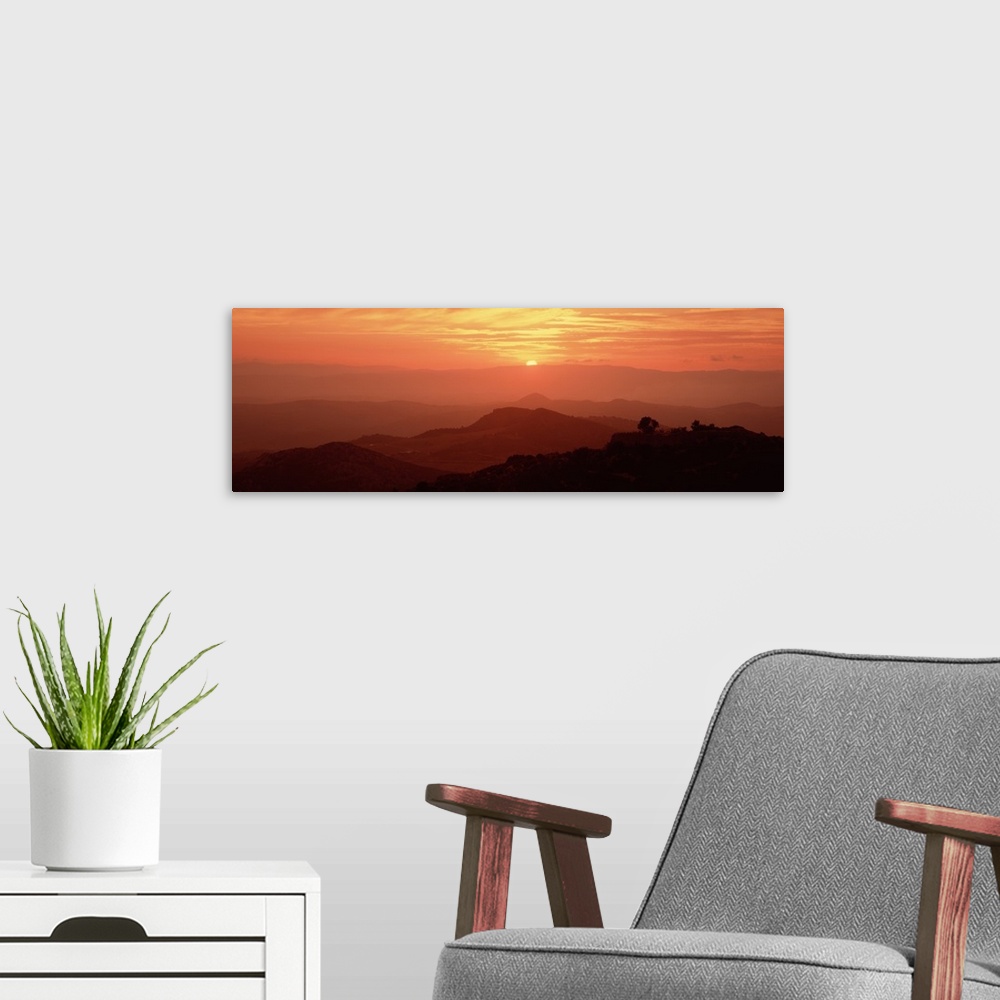 A modern room featuring Giant panoramic photo on canvas of layers of Italian hills with a setting sun in the distance.