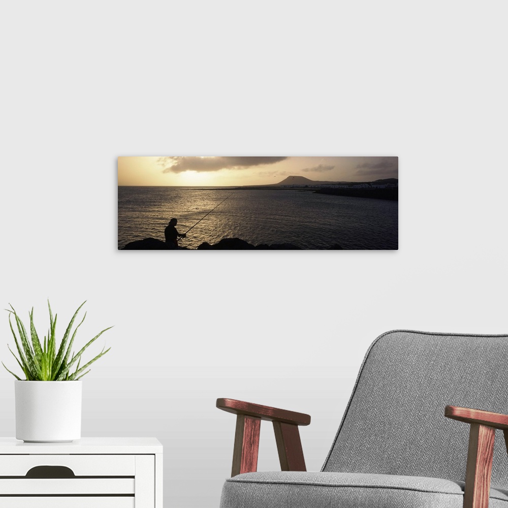 A modern room featuring Silhouette of a person fishing in the sea, La Graciosa Island, Canary Islands, Spain
