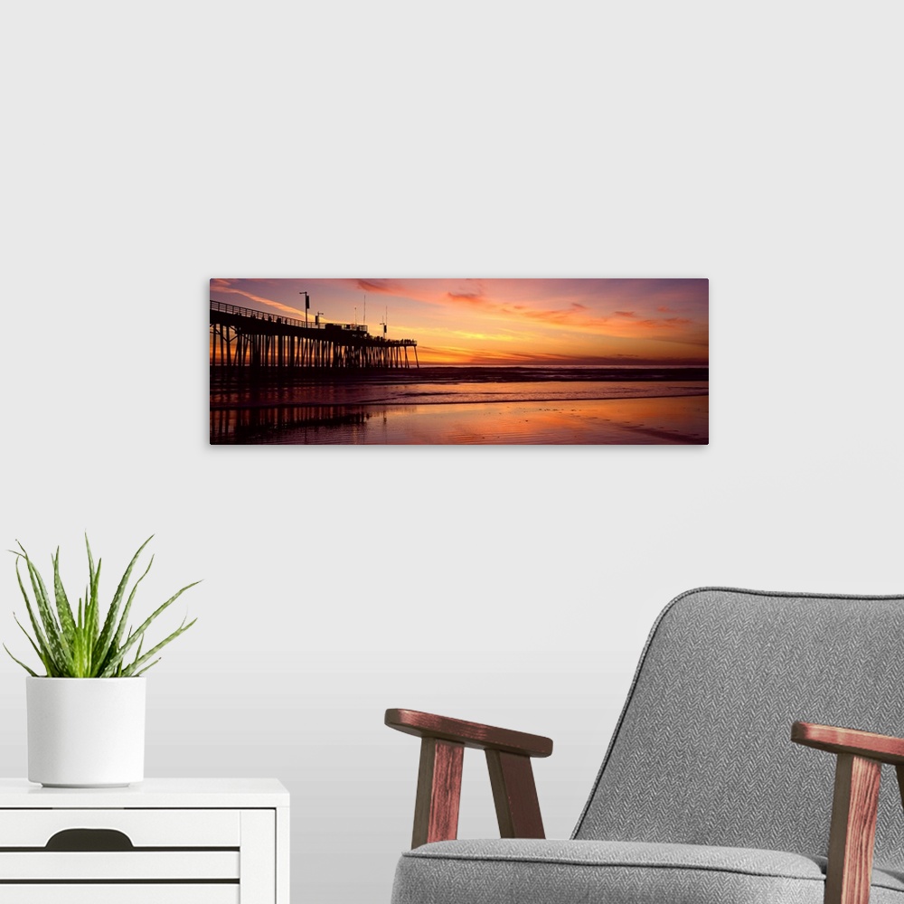 A modern room featuring Sunset at the shore with feathery clouds in the sky and board walk over the ocean.