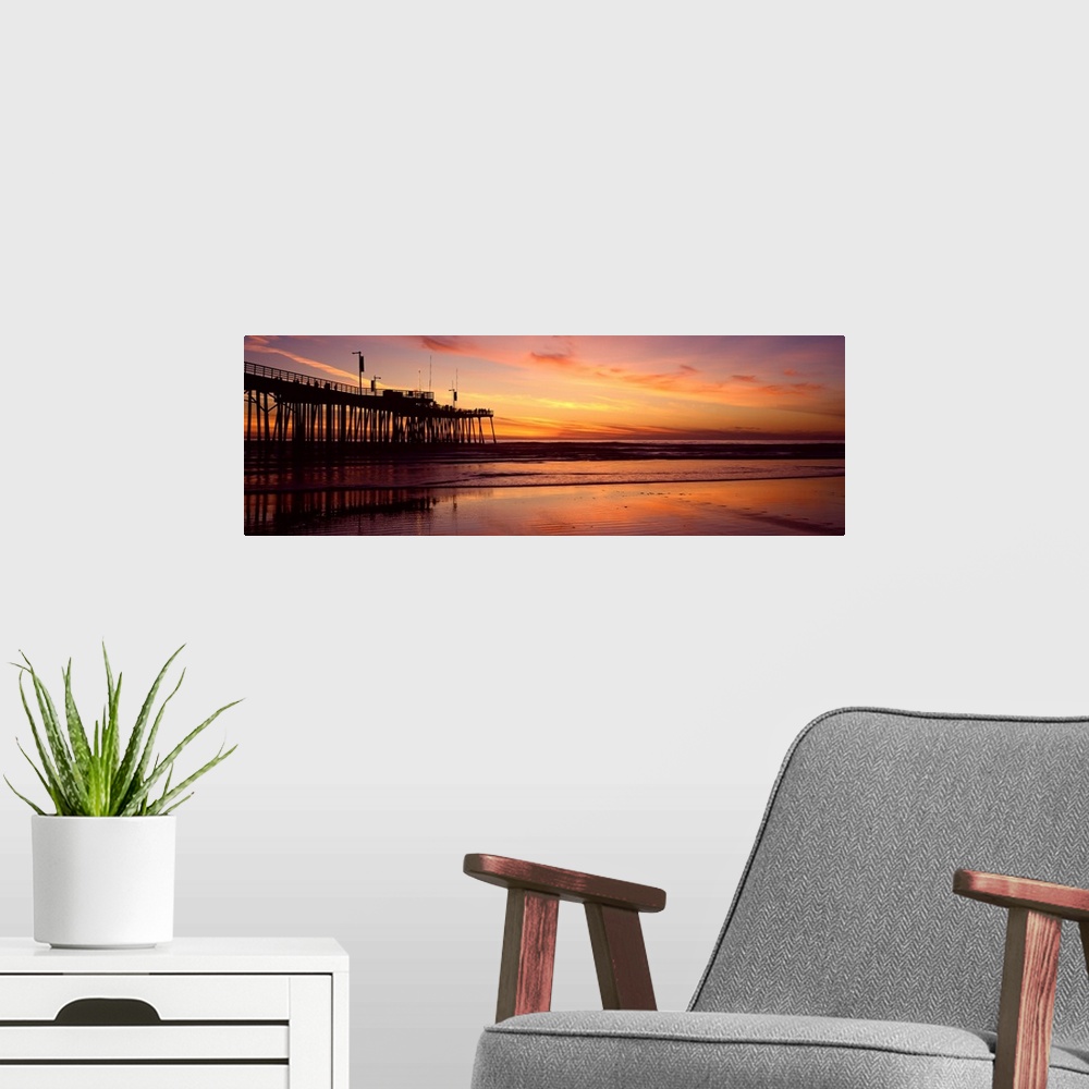 A modern room featuring Sunset at the shore with feathery clouds in the sky and board walk over the ocean.