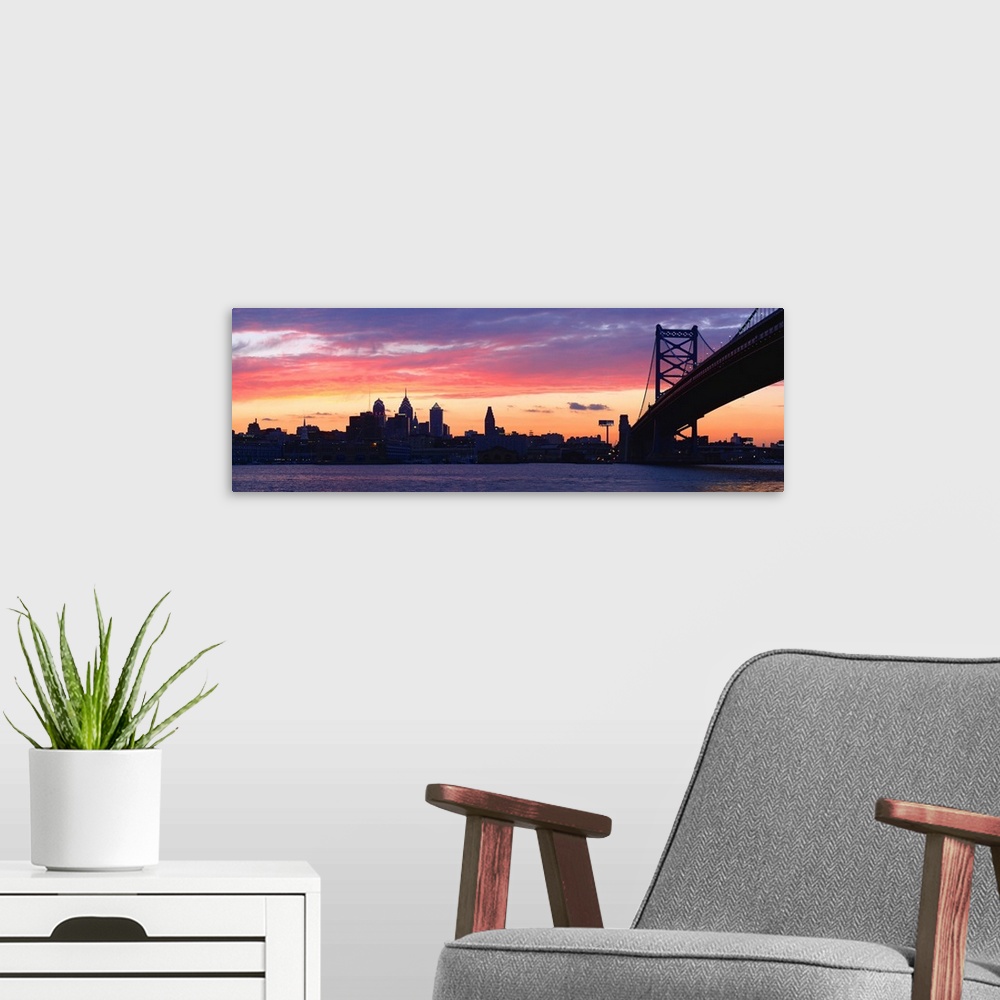 A modern room featuring View from the shoreline under the bridge of pastel-colored clouds over the city skyline at dusk.