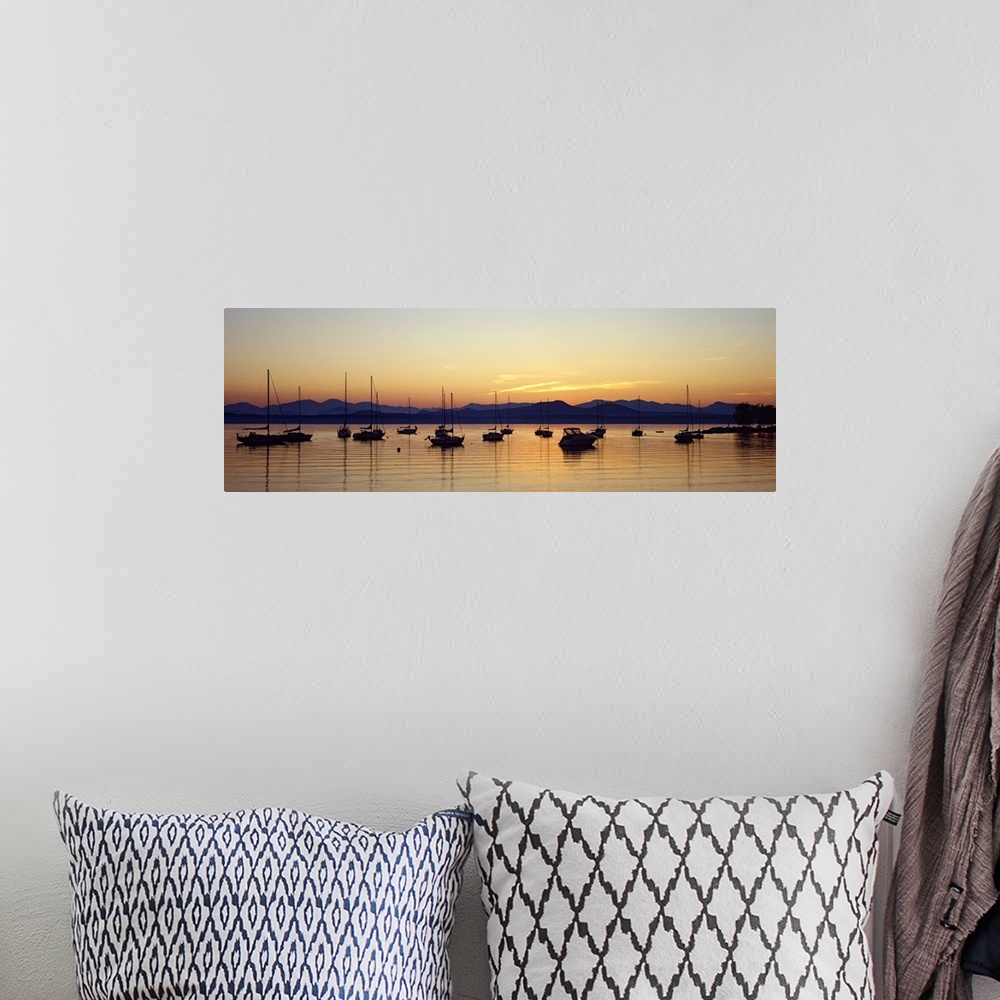 A bohemian room featuring Panoramic photograph of waterway filled with sailboats with mountains in the distance at sunset. ...