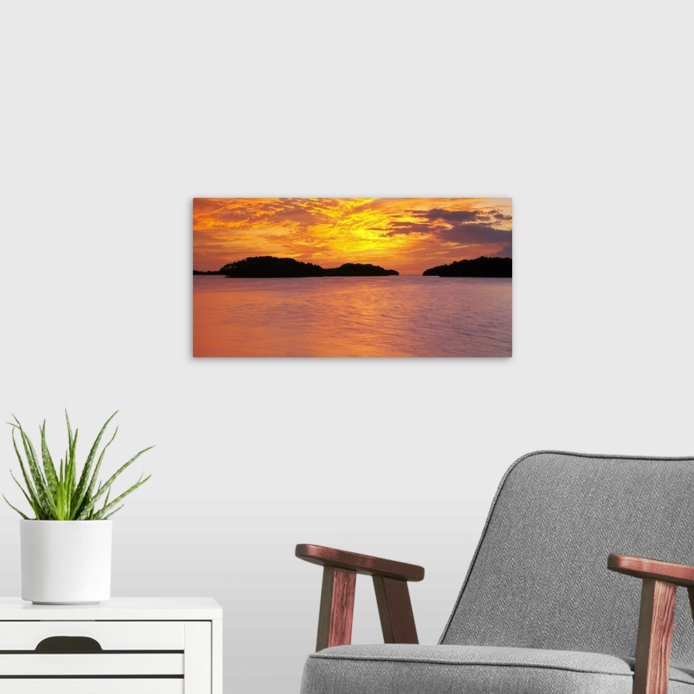 A modern room featuring Large canvas photo of a vibrant sunset reflected in calm waters.