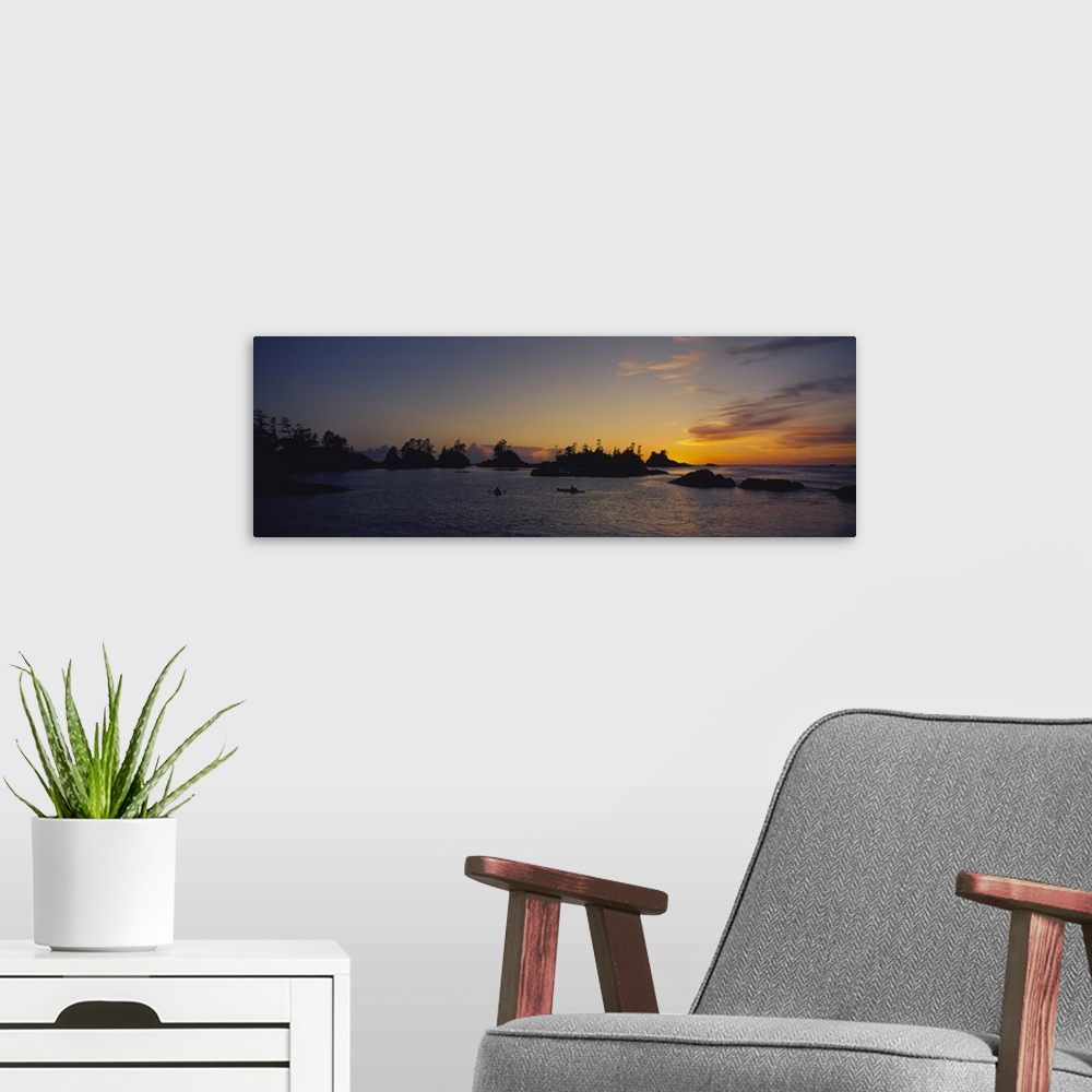 A modern room featuring Tiny islands and boats on the water are silhouetted by the sunset that has gone below the horizon.