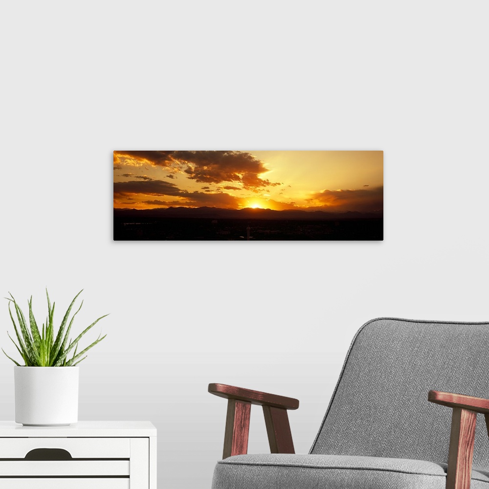 A modern room featuring Land and mountainous terrain are silhouetted as the sun begins to rise from behind them.