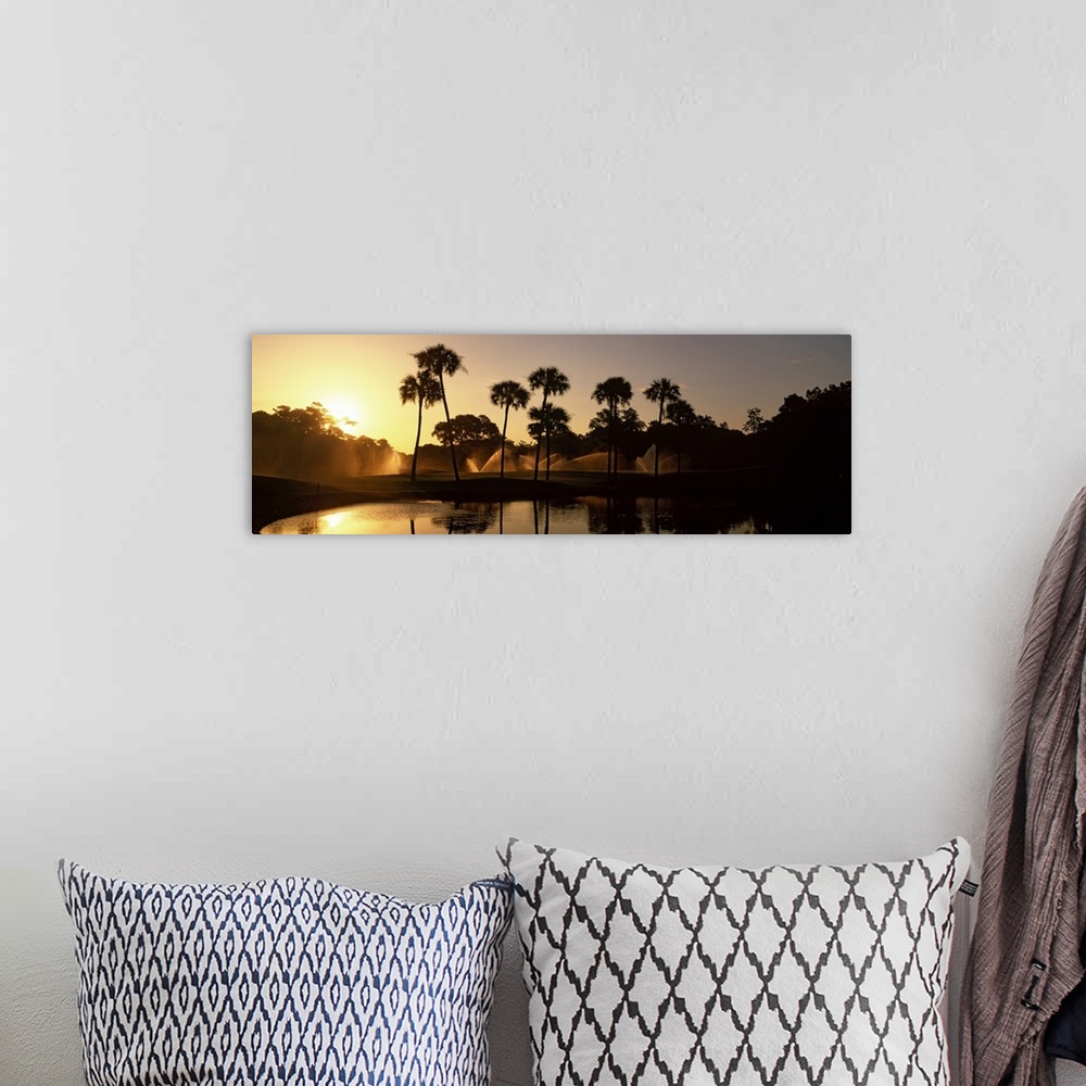 A bohemian room featuring Panoramic wall art of palm trees on a golf course silhouetted against a rising sun with sprinkler...
