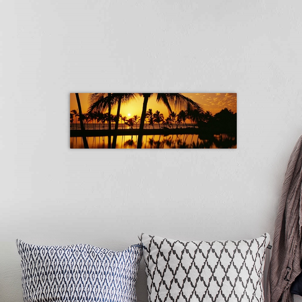 A bohemian room featuring The sun begins to set over the Pacific ocean and silhouettes a line of palm trees.