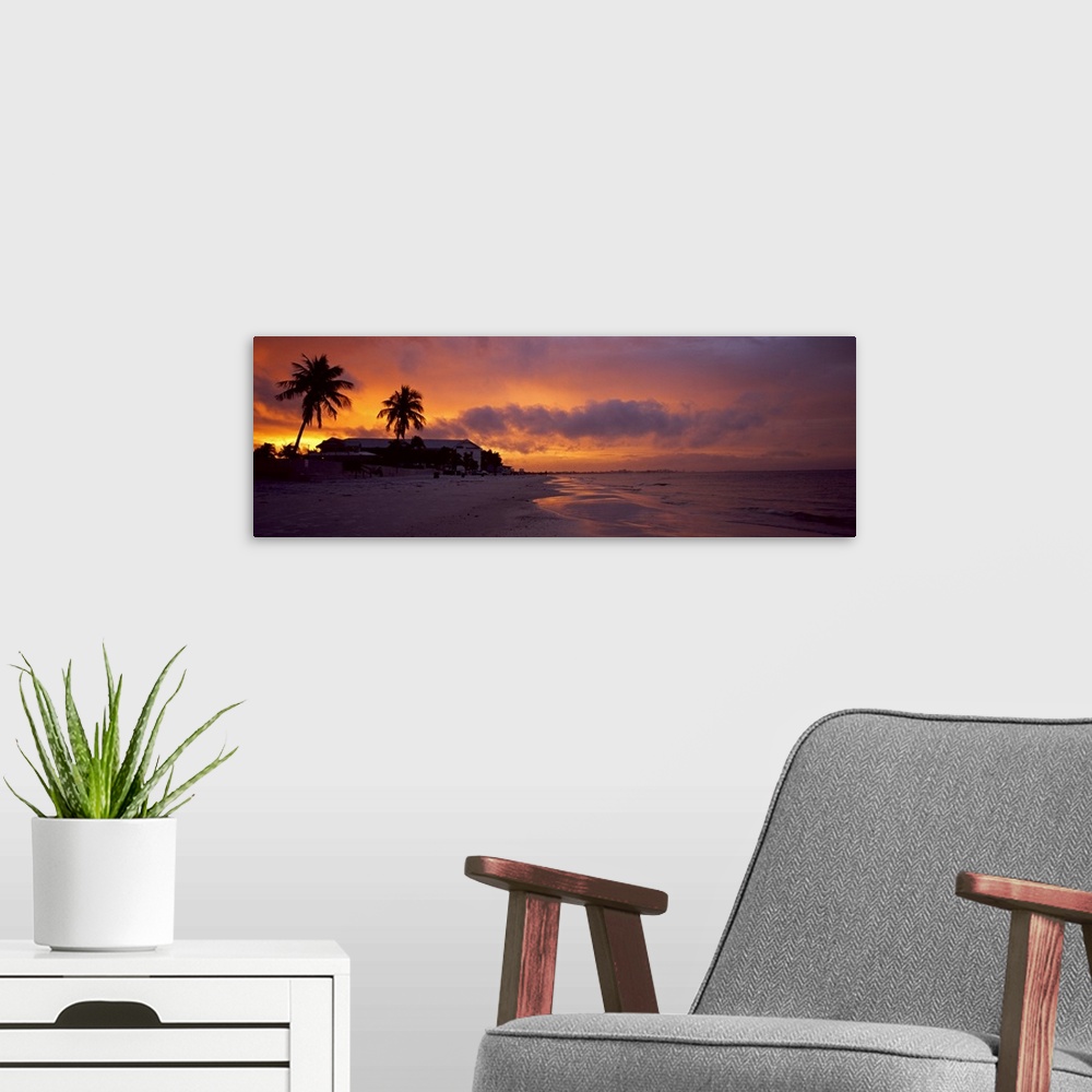 A modern room featuring Large panoramic photograph of a coast in Florida with the sun setting that turns the sky various ...