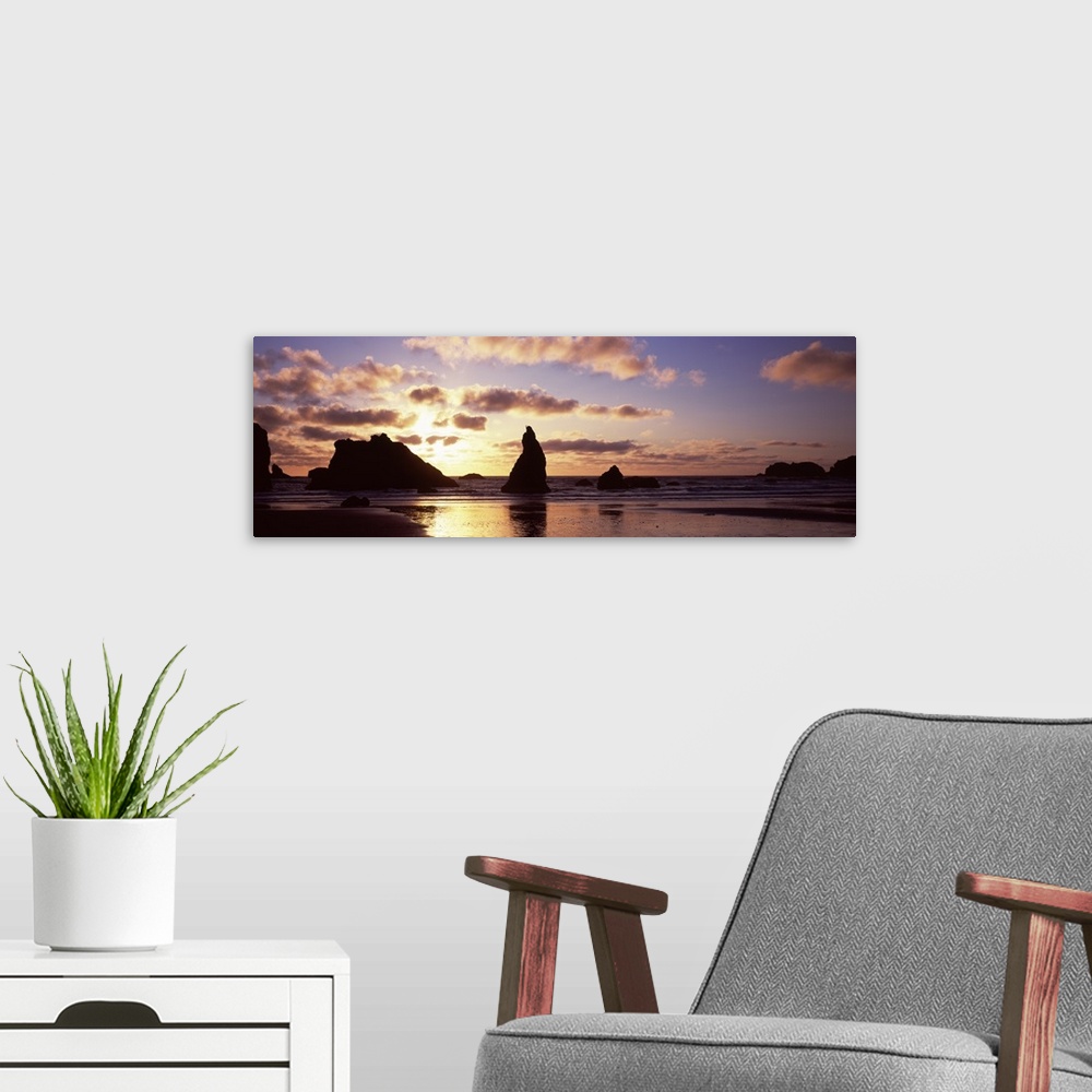 A modern room featuring Photo of the sun setting behind rock formations sticking up in the shallow waters of the ocean cr...